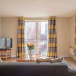 Sitting-room-with-flat-screen-TV-large-and-windows-at-PREMIER-SUITES-Birmingham